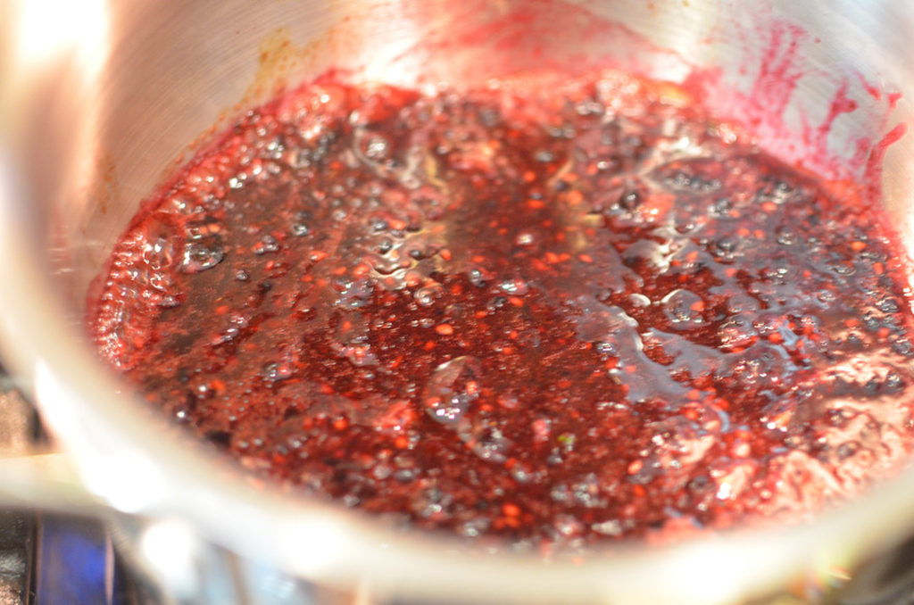 When the ingredients start to warm up, mash and stir the berries with a potato masher.